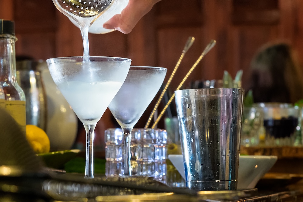 Cocktail being poured into a glass at a bar