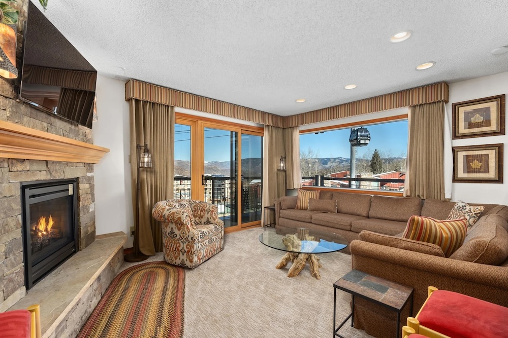 Vacation rental interior with fireplace, cozy furnishing, and window views of the ski lift